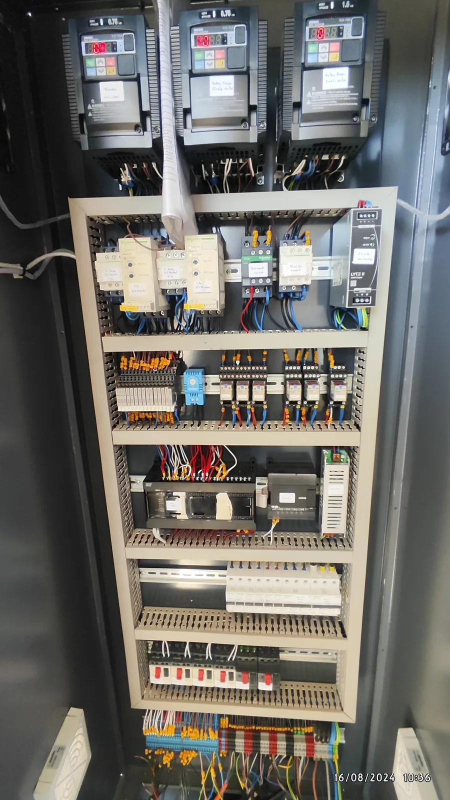 An open control cabinet with wiring, relays and terminal rows